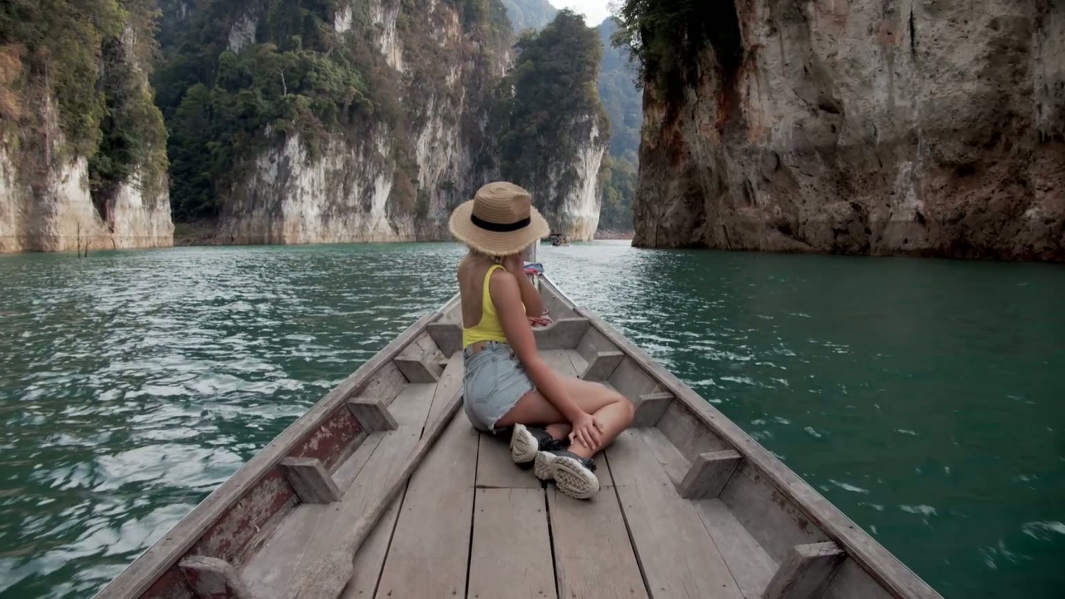A solo traveler on a longtail boat between limestone cliffs in Thailand