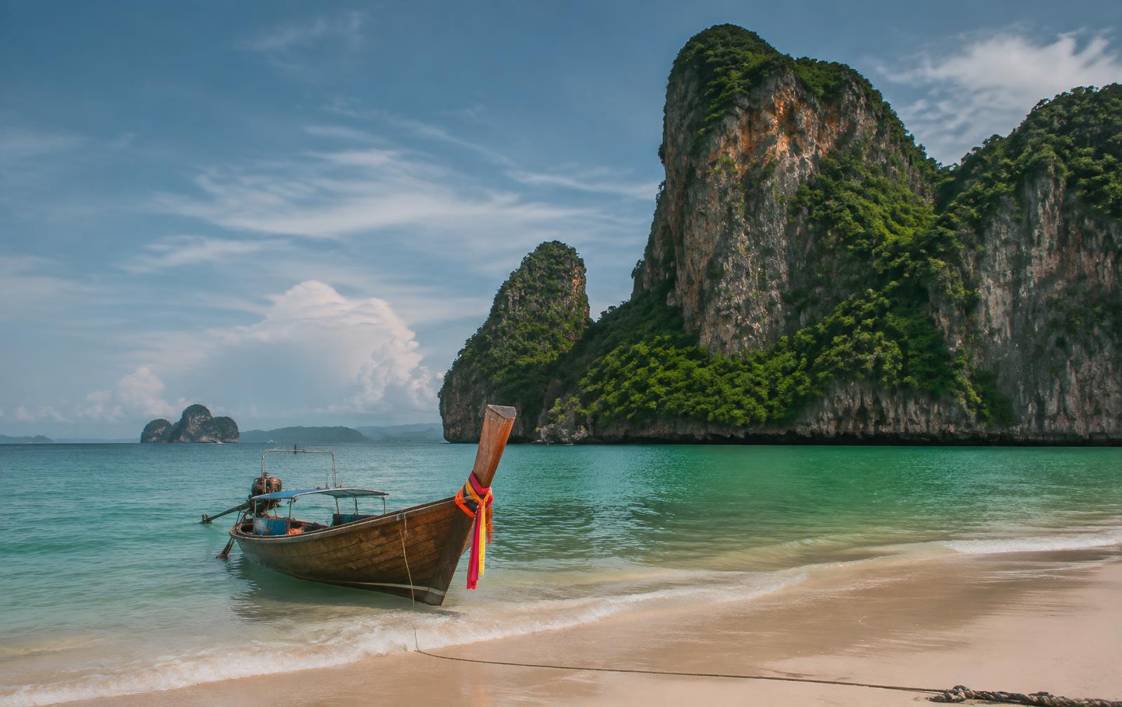 Limestone cliffs and a longtail boat on a Krabi beach