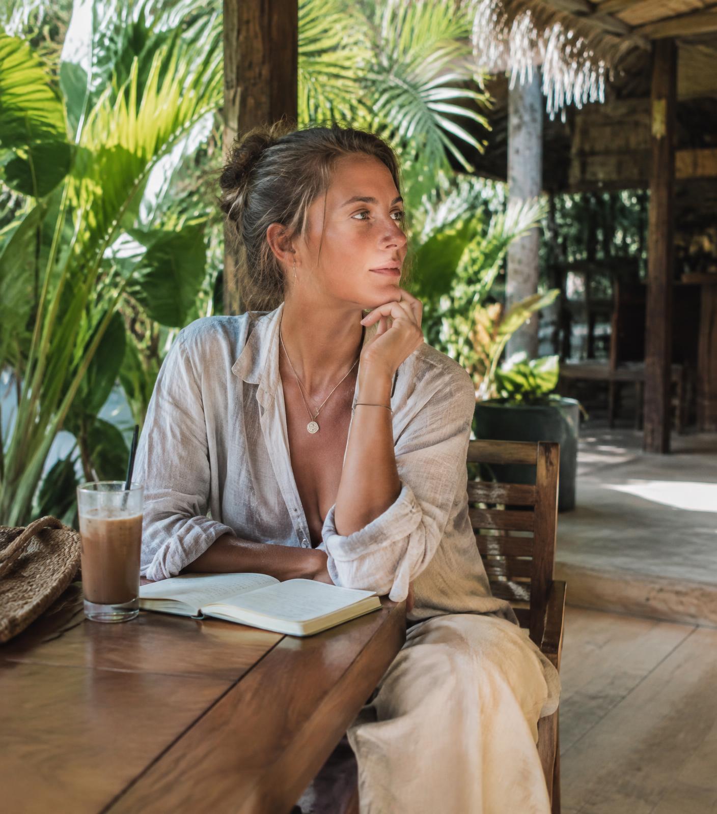 Solo traveler writing in a notebook at an open-air café in Thailand